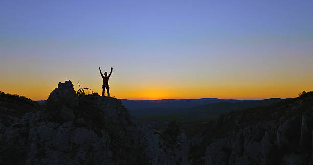 istock Sunset triumph: A climber stands victorious on a rocky peak, embracing the day's final light 2217423810
