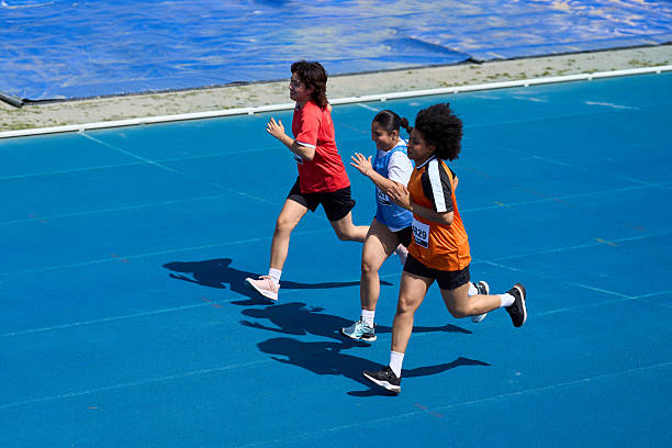 Two boys running in race at Sports day, crowd of spectators out of focus in distance
