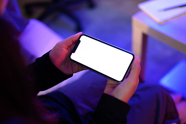 istock Hands holding smartphone with a blank white screen in a neon lit environment 2217427199