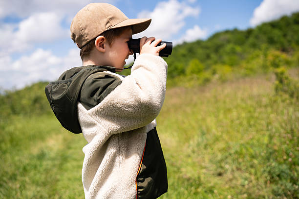 istock Child birdwatching in a grassy outdoor setting uses binoculars 2217433735