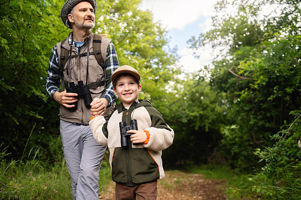 istock Father and son birdwatching together in a lush green forest trail 2217434285