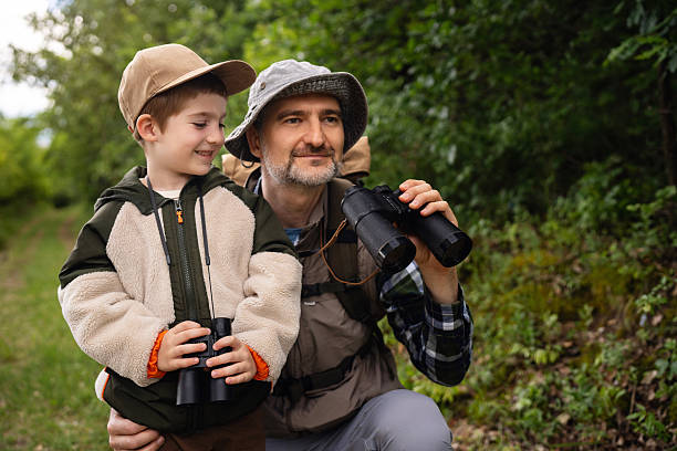 istock Father and son birdwatching together with binoculars in a forest trail setting 2217436440