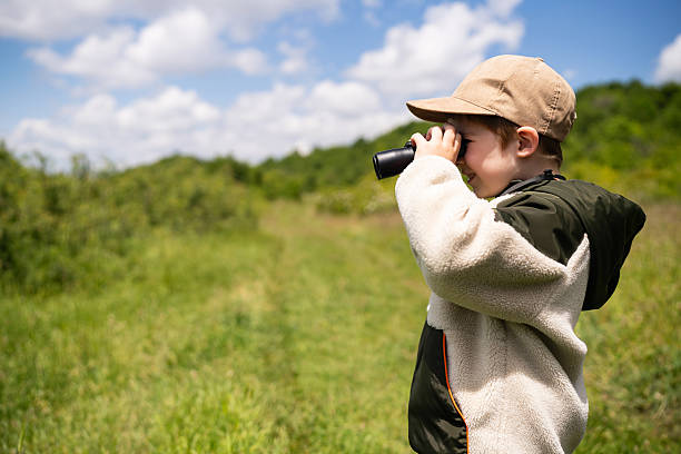 istock Young boy birdwatching with binoculars in a lush outdoor setting 2217436532