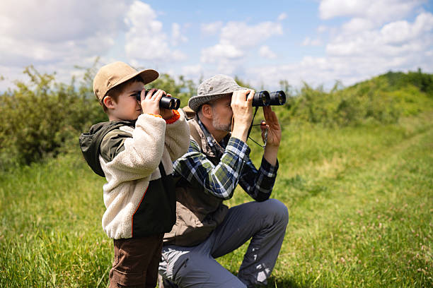 istock Father and son birdwatching together in a grassy landscape with binoculars 2217437143