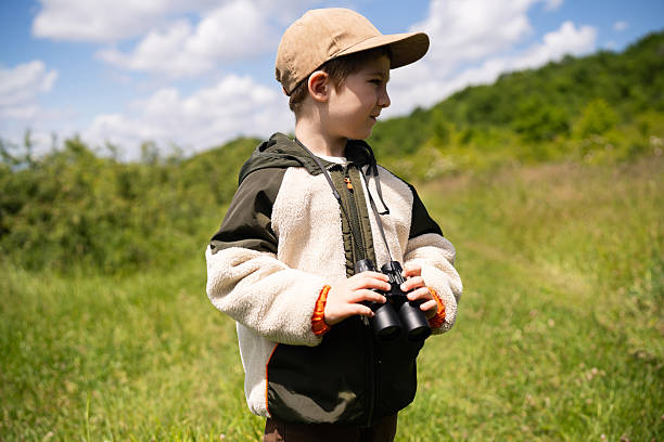 istock Young boy exploring nature with binoculars on a sunny day outdoors 2217437238