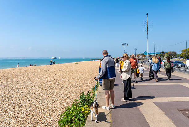 Southsea, UK. 18 May 2025. People walking on Southsea promenade on a sunny day