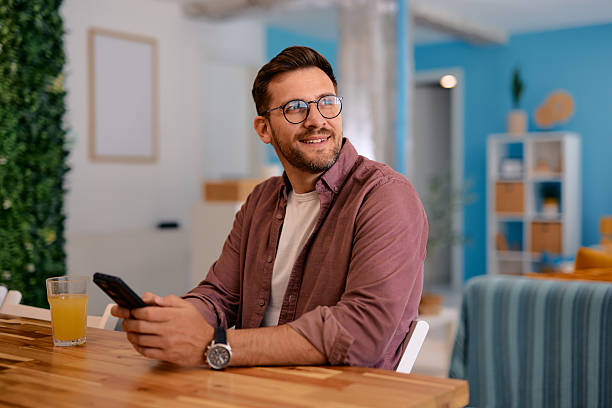 istock Young man using smartphone and smiling at home 2217440227