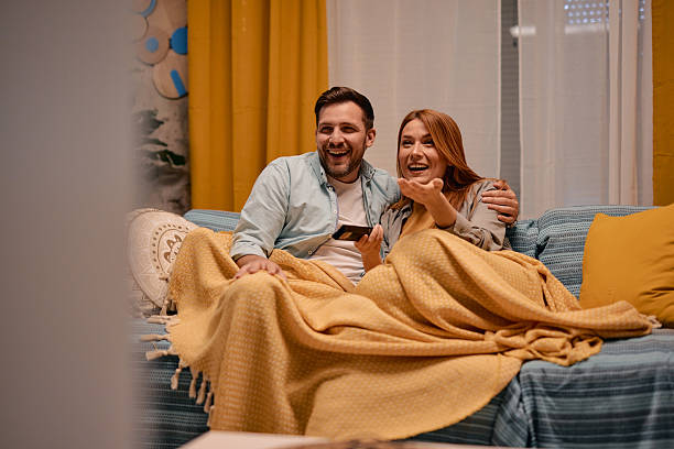 istock Couple relaxing on sofa, watching television and talking at home 2217440515