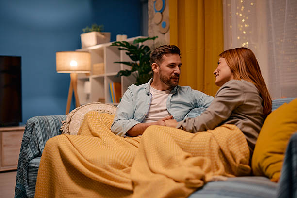 istock Couple relaxing on sofa, holding hands and talking at home 2217440601