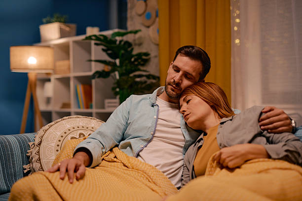 istock Serene couple sleeping on sofa under cozy blanket at home 2217440603