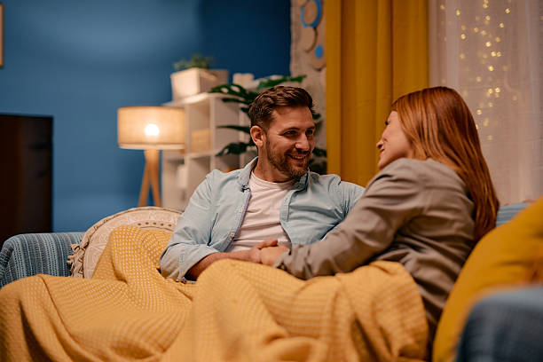 istock Couple relaxing on sofa, holding hands and talking at night 2217440604