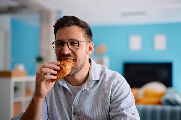 istock Man enjoying eating a croissant at home 2217440622