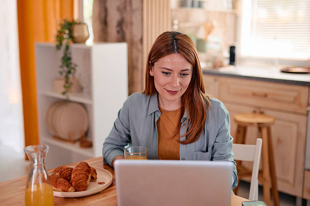 istock Young woman working from home having breakfast and using laptop 2217440776