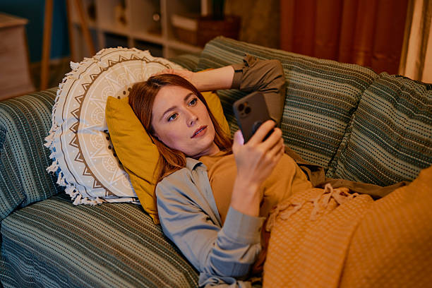 istock Woman relaxing on sofa using smartphone at home 2217440824