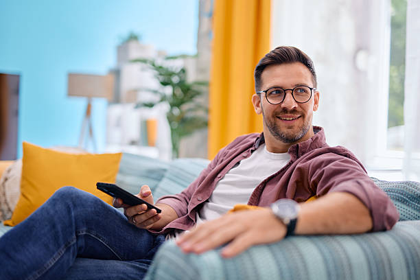 istock Man relaxing on sofa using remote control, enjoying his free time at home 2217440980