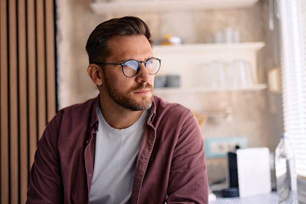 istock Pensive young man looking away while sitting in kitchen at home 2217440984