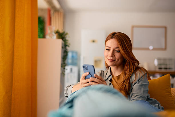 istock Young woman relaxing on sofa using mobile phone at home 2217442052