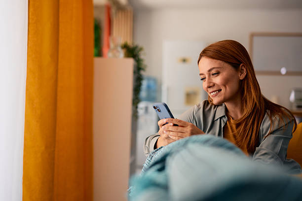 istock Woman relaxing on sofa using mobile phone at home 2217442059