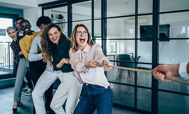 istock Playful colleagues having fun while playing tug-of-war in the office. 2217443178