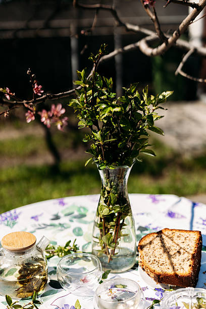istock A rustic outdoor table arrangement featuring a vase with fresh greenery, glass jars, and homemade bread on a plate. Perfect for garden-inspired themes and food-related branding 2217447132