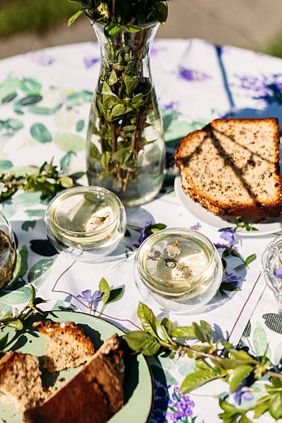 istock A pleasant table setup outdoors featuring a plate of bread, nuts in jars, and greenery in a vase. Perfect for themes of rustic living, garden parties, and food-related branding 2217447137