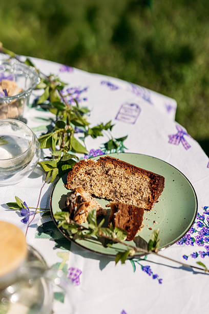 A rustic outdoor table setting featuring a homemade slice of bread on a green plate, surrounded by greenery and glass jars. Perfect for food photography, lifestyle branding, and rustic themes.