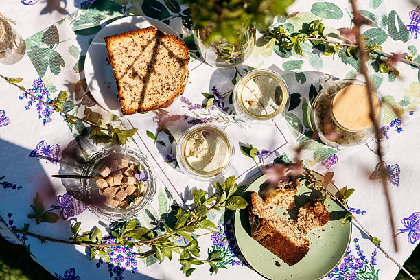 istock A pleasant table setup outdoors featuring a plate of bread, nuts in jars, and greenery in a vase. Perfect for themes of rustic living, garden parties, and food-related branding 2217447153