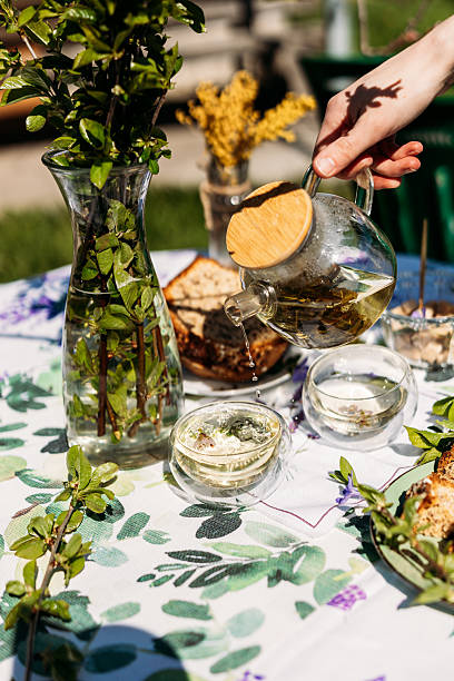 istock A rustic outdoor table setting with a vase of fresh greenery, a hand pouring tea into a glass, and homemade snacks. Perfect for lifestyle branding, garden parties, and seasonal dining 2217447159