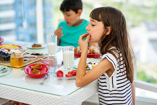 istock Two siblings having breakfast on the balcony, while the girl is eating tomatoes 2217449813