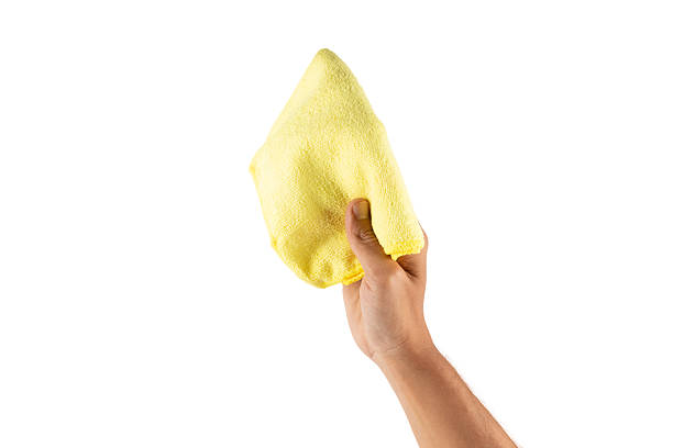 istock Male hand using a yellow cleaning cloth isolated on white background 2217450945