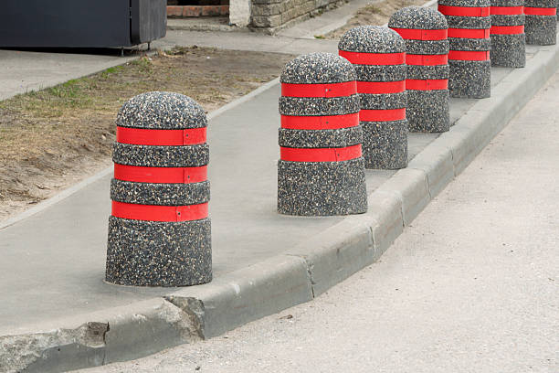 istock Concrete bollards with bright red stripes line urban sidewalk, creating visual rhythm and enhancing pedestrian safety in cityscape. 2217455054