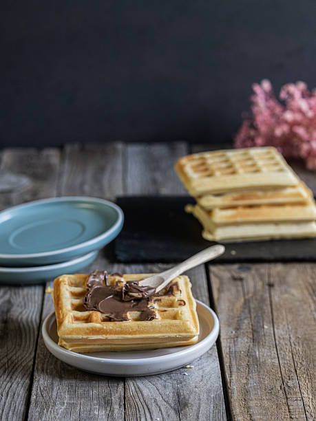 istock Rustic breakfast setup with waffles topped with chocolate spread, served on a wooden table in a cozy, home-style atmosphere. 2217458742