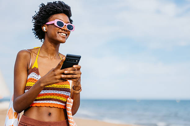 istock Young Black Woman Using Her Phone On The Beach In Spain 2217463926