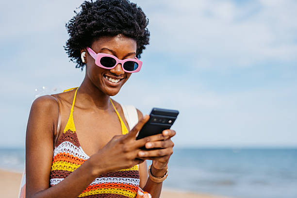 istock Young Black Woman Using Her Phone On The Beach In Spain 2217464468