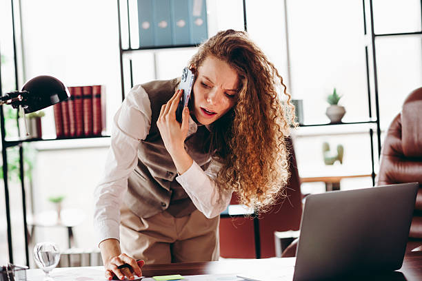 istock Young Businesswoman Working in Office Discussing Tasks Over Phone While Taking Notes 2217468936