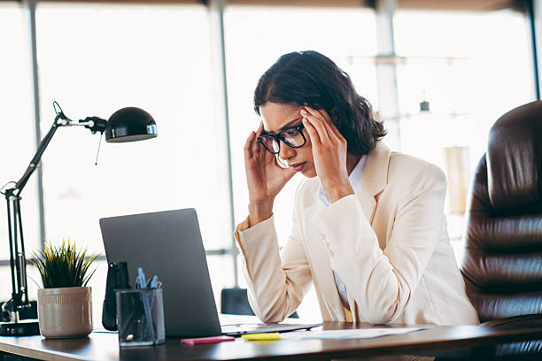 istock Professional businesswoman in a formal office setting working on a laptop and analyzing documents 2217469454