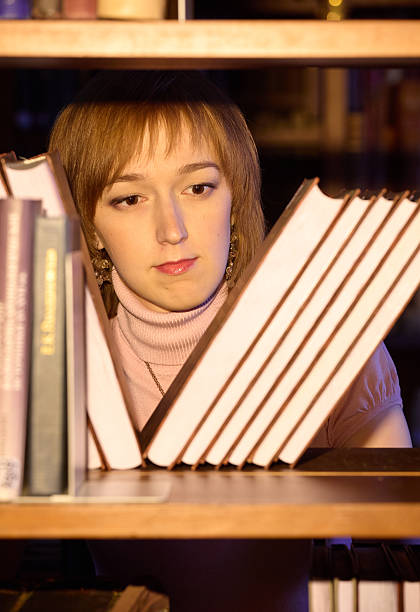 A librarian searches for a book on a bookshelf