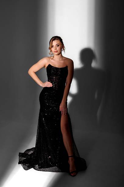 istock Model poses elegantly in a shimmering black dress under dramatic lighting in a studio setting 2217472419