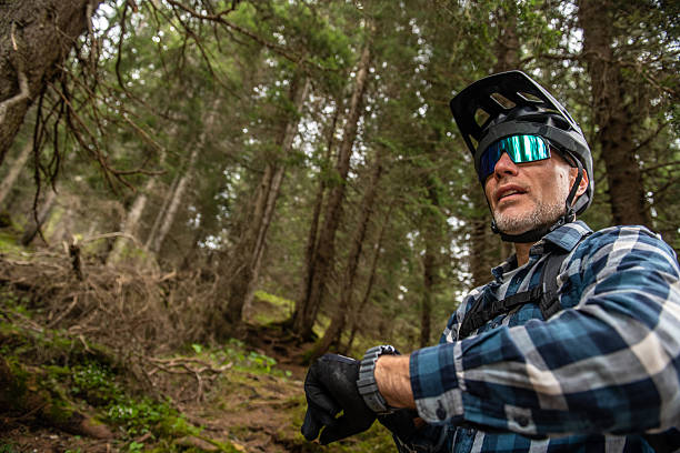 istock Mountain biker uses smartwatch on forest trail in mountains 2217475003
