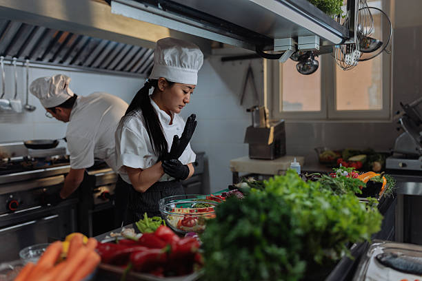 istock Female chef wearing black gloves preparing a meal in a restaurant kitchen 2217486892