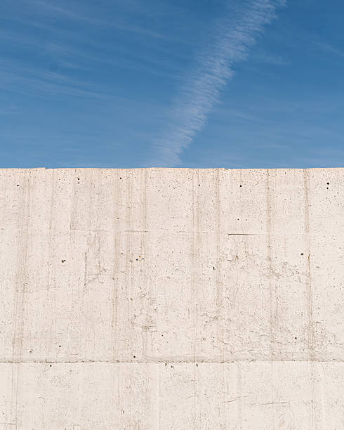 istock Bare concrete wall rises into bright blue sky, minimalist urban landscape symbolizing strength, modernity, and architectural simplicity. 2217486950