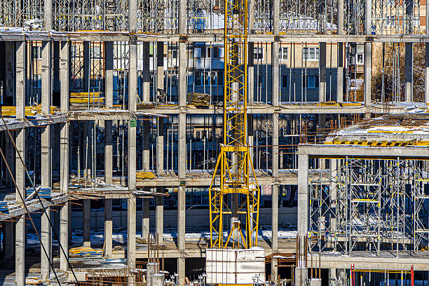 istock Tall building under construction with scaffolds,Freestanding tower crane on a building site.Building construction site work against blue sky 2217487813