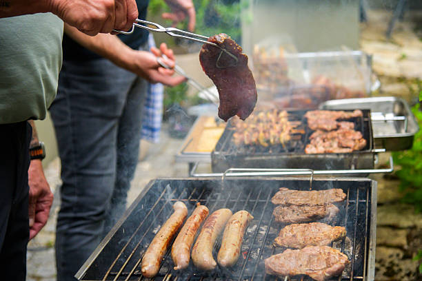 A vibrant German barbecue setting, featuring grilling sausages and steaks, with people engaged in cooking outdoors. Perfect for concepts of socializing, food, and summer traditions.