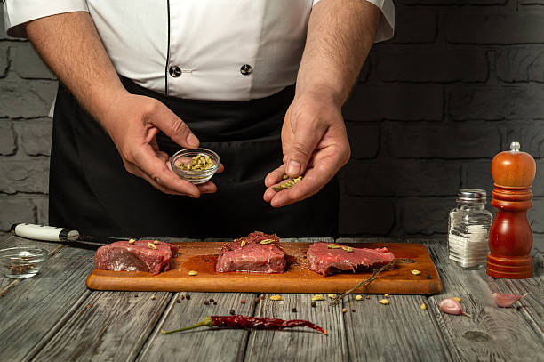 istock In a rustic kitchen, a chef skillfully prepares beef cuts by sprinkling spices and herbs, showcasing a variety of flavors and culinary expertise 2217493304