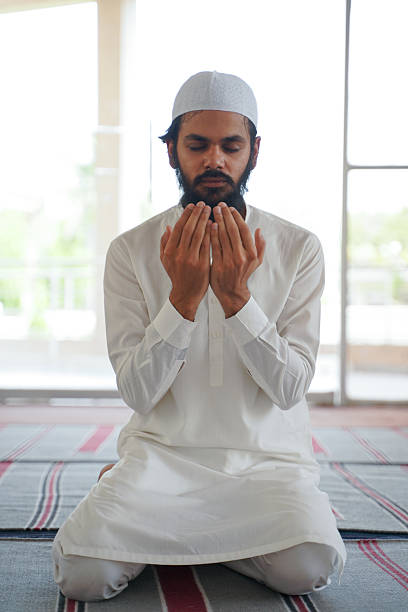 istock Indian Muslim man in white prays with hands raised in supplication. 2217496028