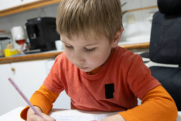 istock Young child drawing on paper at home, concentrating on his creative activity 2217497280