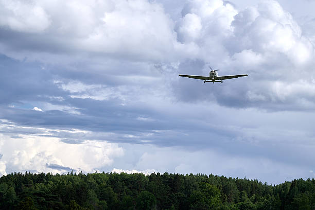 istock Small airplane flying low with majestic clouds and a forest in the background. 2217497418