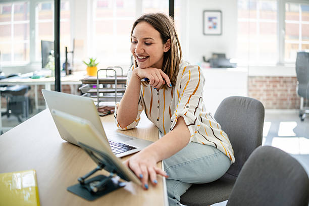 istock Young businesswoman engaged in confident discussion while working at a modern office desk with technology 2217498394