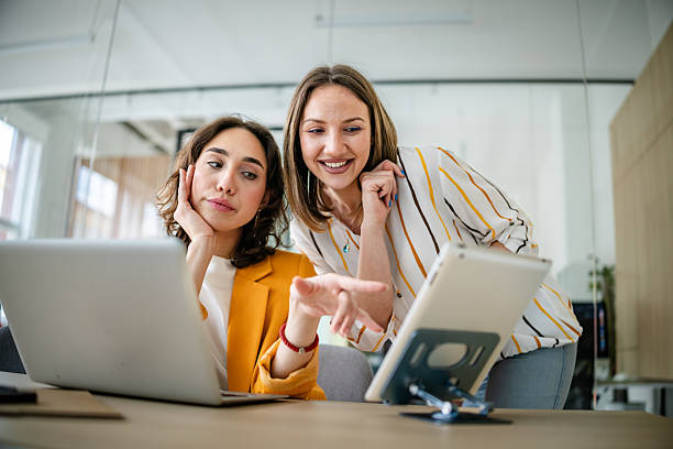istock Young businesswomen engage in a productive discussion over technology in a modern office setting 2217501112