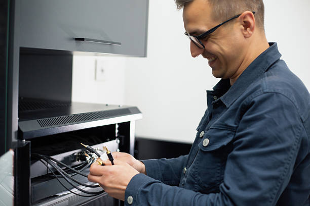 Smiling technician connecting audio cables to stereo receiver in living room